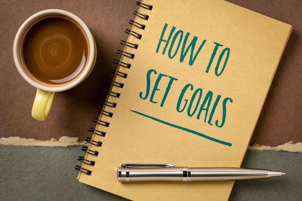 How to set goalsと書かれたノートとコーヒー